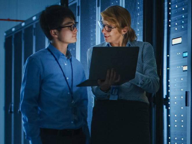 Man and woman standing holding a laptop focusing